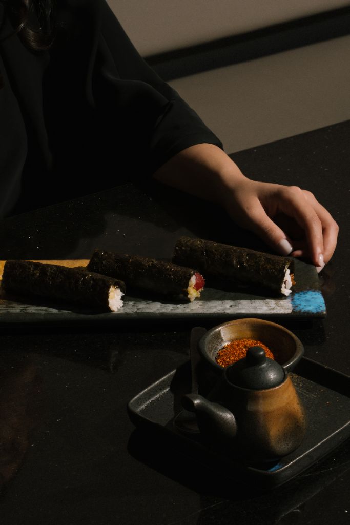 Chef's hands preparing sushi roll